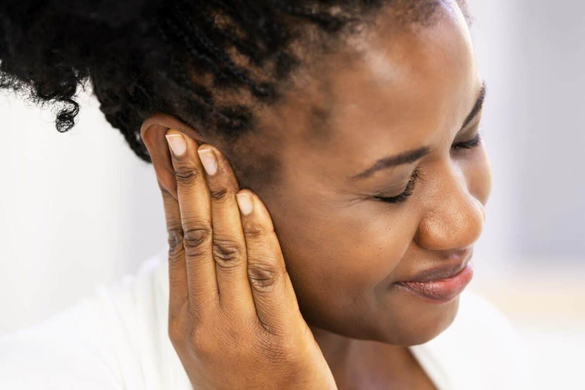 Woman with ear pain, holding the ear.